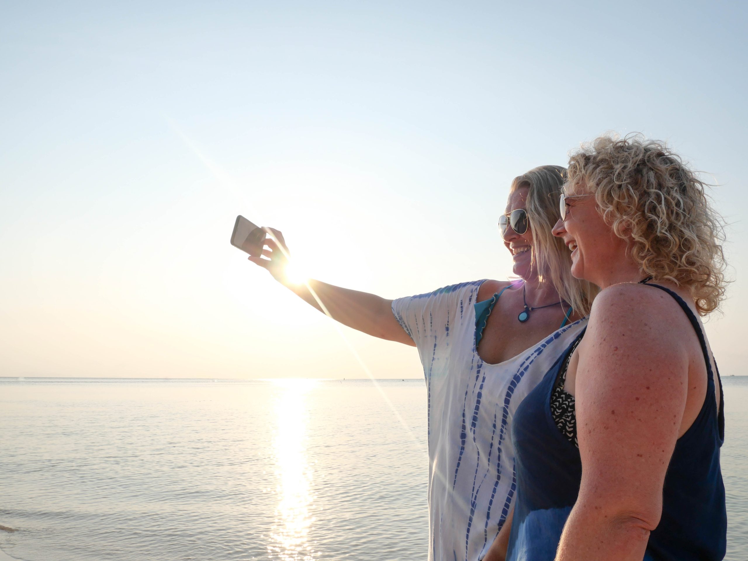 Two funny senior women making selfie on smartphone at sunset beach Two funny senior women making selfie on smartphone at sunset beach.